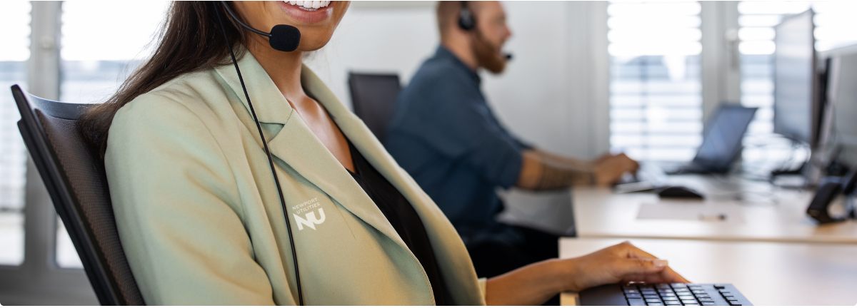 Smiling woman wearing a headset and an NU blazer while sitting at a desk