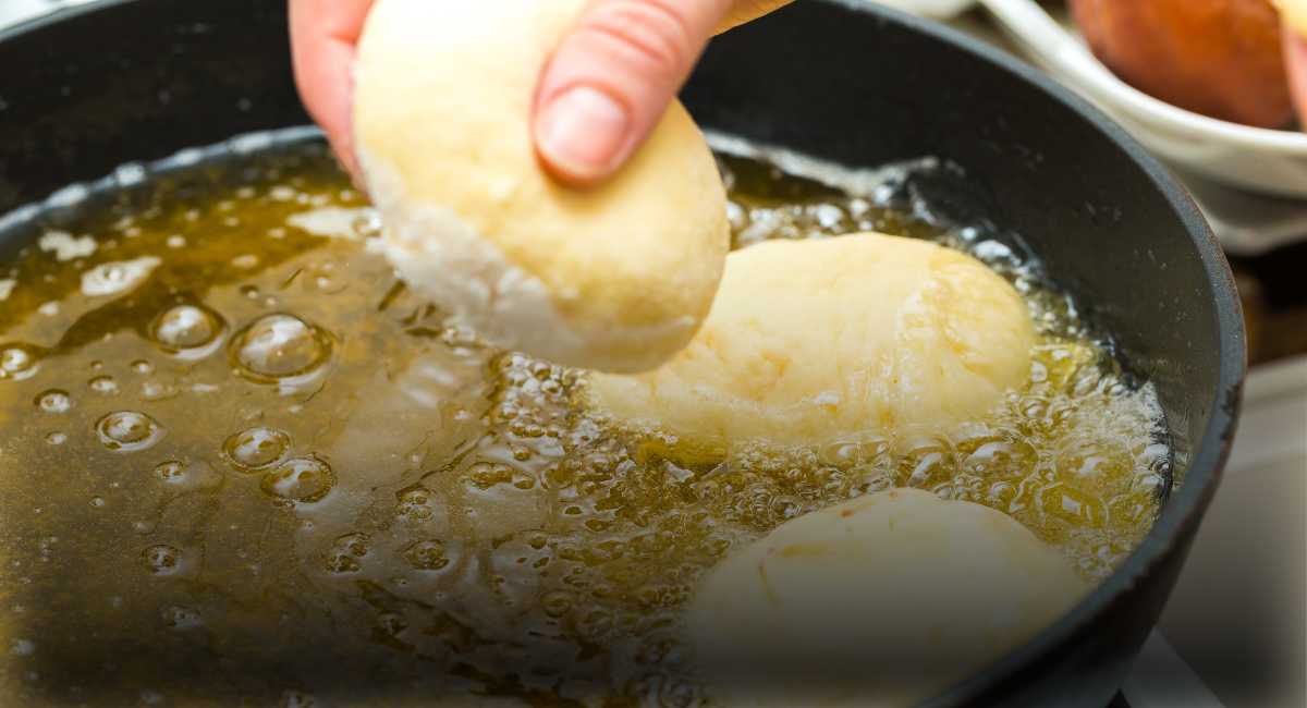 A hand laying dough into a frying pan full of oil to show the Fats, Oils, and Grease Control program page header